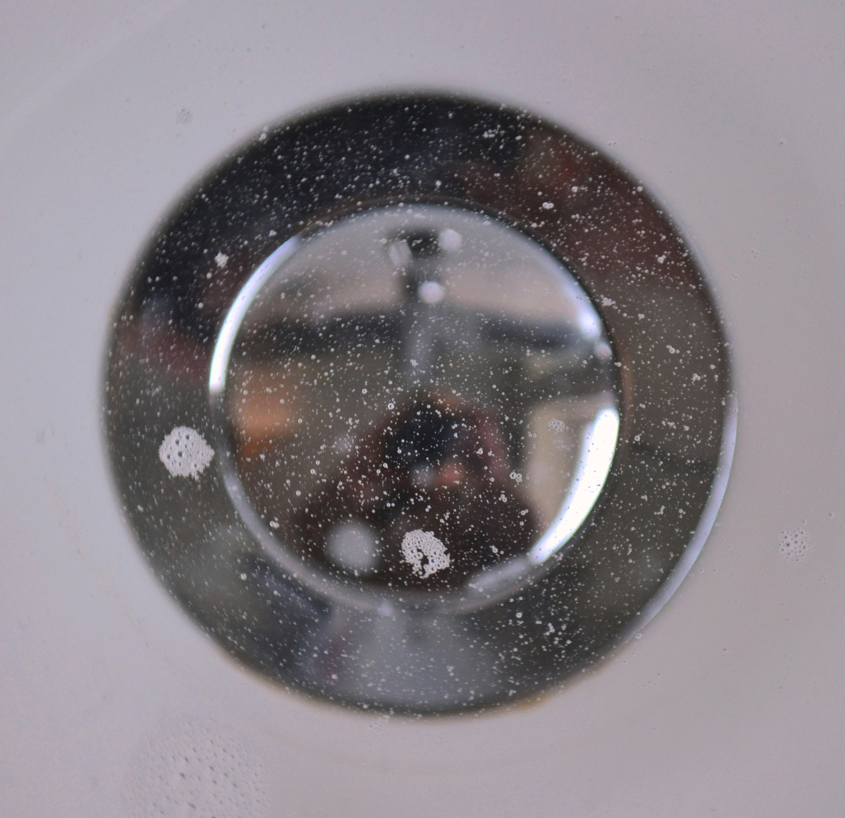a close up of a white sink with water droplets